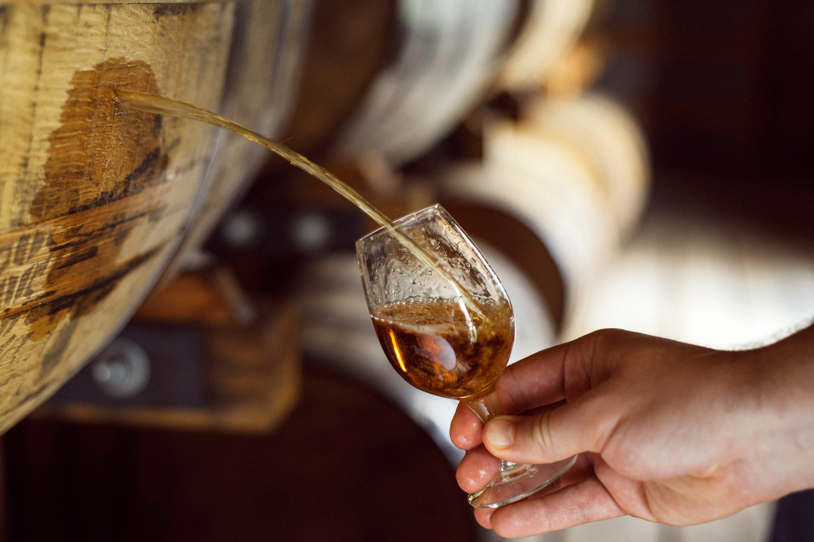 Whiskey being poured from a barrel into a glass.